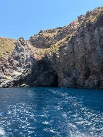 A stunning view of a rocky coastline featuring a cave entrance, showcasing the natural beauty of the ocean and surrounding landscape.