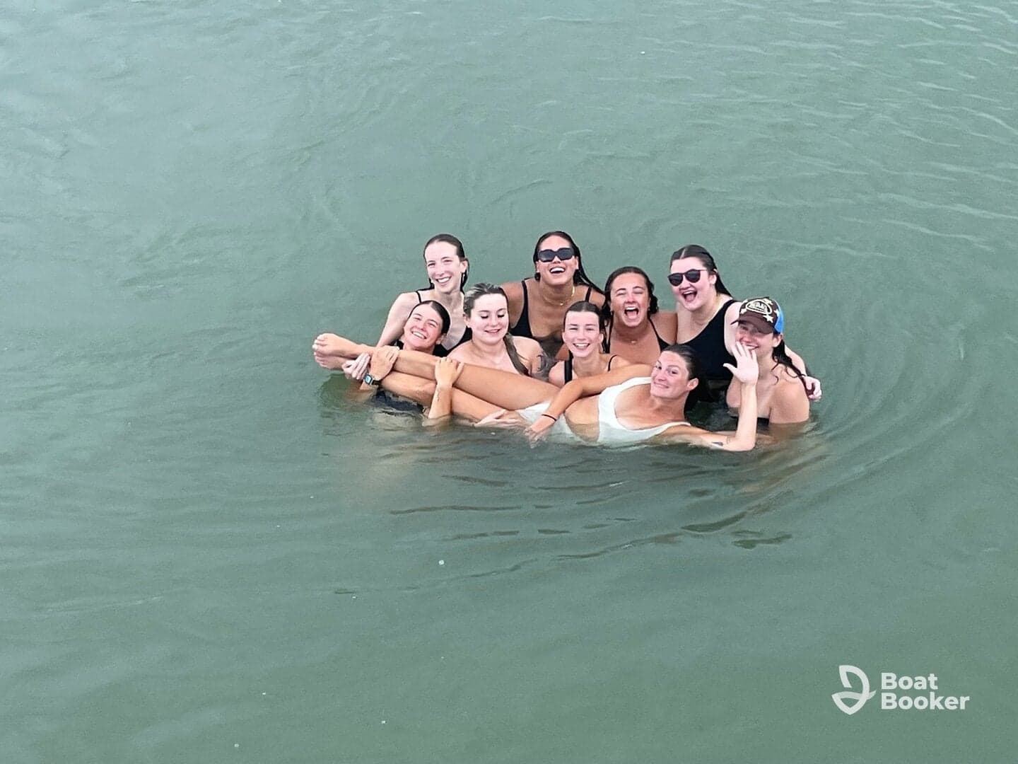 A joyful group of friends enjoys a fun day swimming together in the water, capturing the essence of friendship and celebration on their boating adventure.