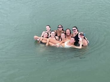 A joyful group of friends enjoys a fun day swimming together in the water, capturing the essence of friendship and celebration on their boating adventure.