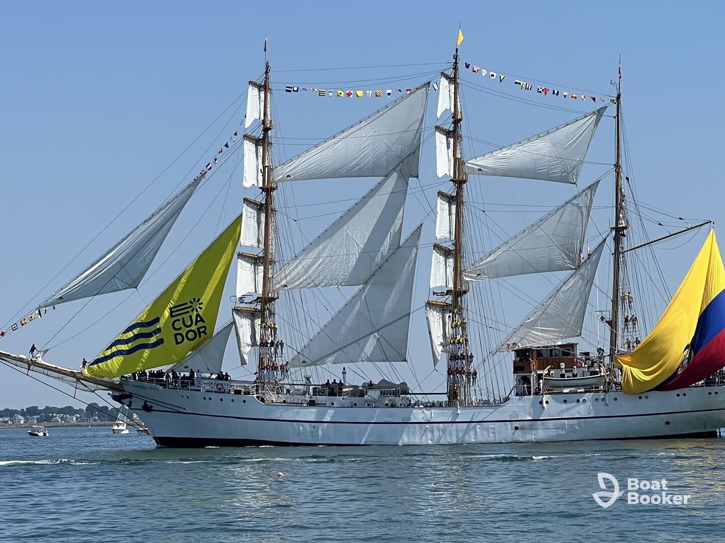 A majestic sailing ship adorned with vibrant flags and the Ecuadorian banner, gracefully navigating the waters — a stunning display of maritime tradition.