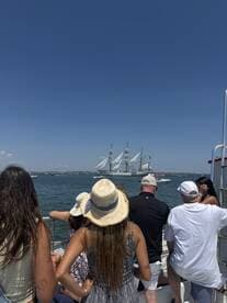 A group of guests enjoys a scenic view of a majestic sailing ship while aboard their own vessel, capturing the essence of a perfect day on the water.