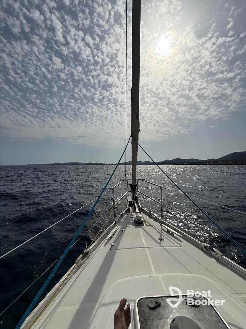 A captivating view from the front of a sailboat, showcasing the vast ocean and dramatic cloud patterns above, perfect for sailing enthusiasts.