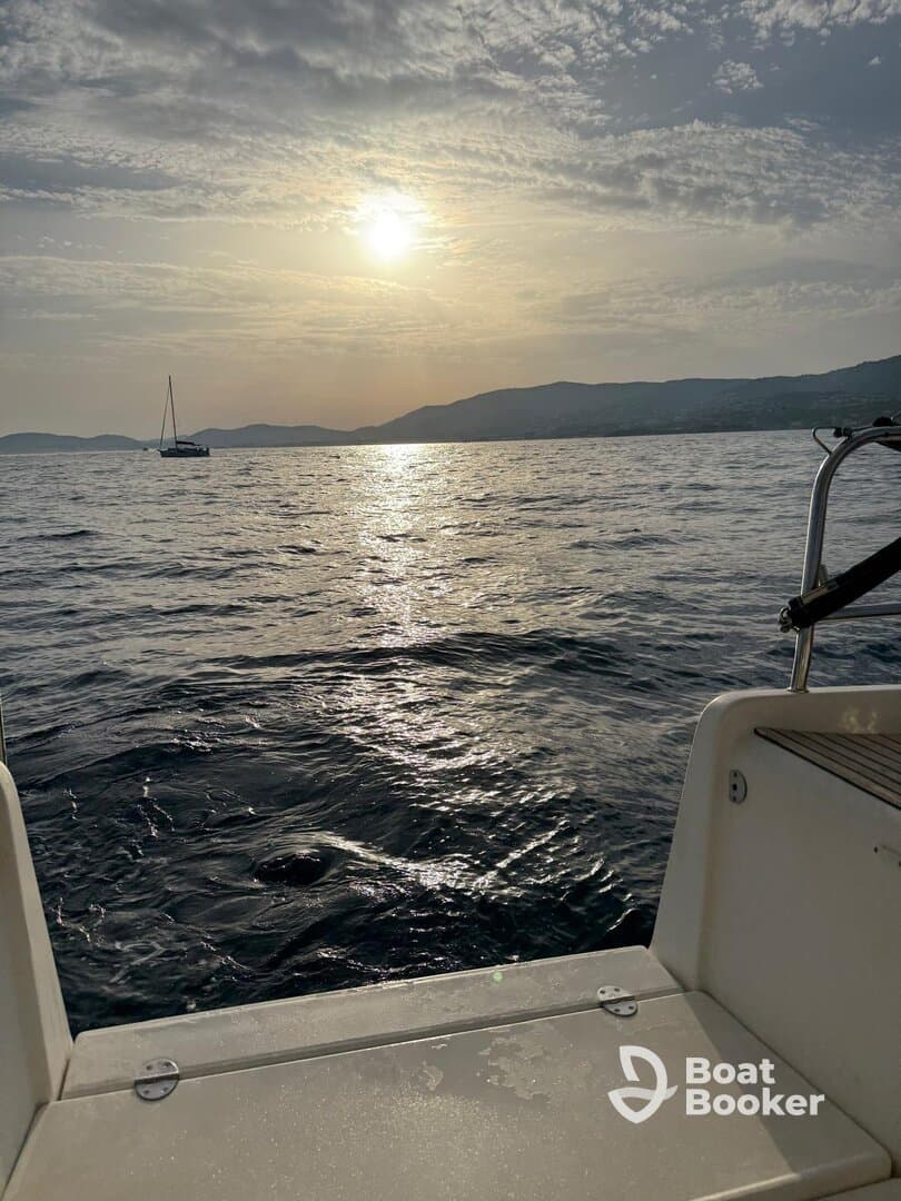 A serene view from the deck of a boat at sunset, showcasing the tranquil waters and distant hills, perfect for peaceful evening cruises.