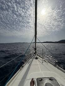 A captivating view from the front of a sailboat, showcasing the vast ocean and dramatic cloud patterns above, perfect for sailing enthusiasts.