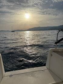 A serene view from the deck of a boat at sunset, showcasing the tranquil waters and distant hills, perfect for peaceful evening cruises.