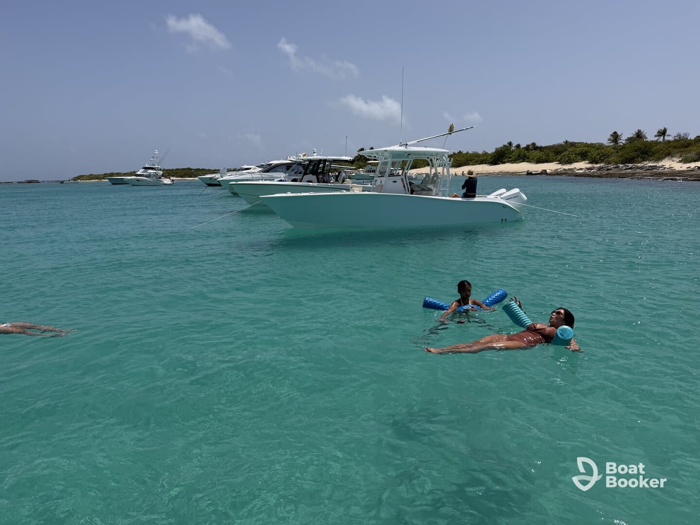 A family enjoys a sunny day at the beach, with a child playing in the water and an adult relaxing while floating — a perfect scene for summer fun and family bonding.