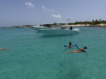 A family enjoys a sunny day at the beach, with a child playing in the water and an adult relaxing while floating — a perfect scene for summer fun and family bonding.