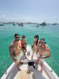 A lively group of friends poses on the deck of a boat, enjoying a sunny day on the water — perfect for summer adventures and memorable outings.
