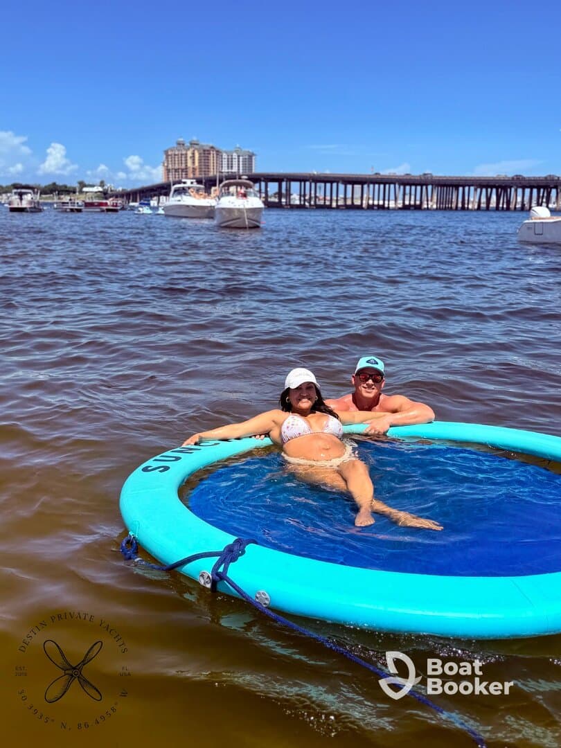 A couple enjoys a sunny day on a floating mat in the water, perfect for relaxation and fun under the sun.