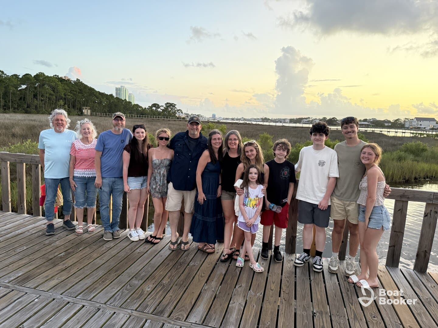 A joyful family gathers for a group photo at sunset, capturing a memorable moment by the water — perfect for family reunions or vacations.