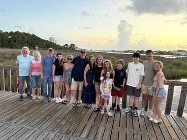 A joyful family gathers for a group photo at sunset, capturing a memorable moment by the water — perfect for family reunions or vacations.
