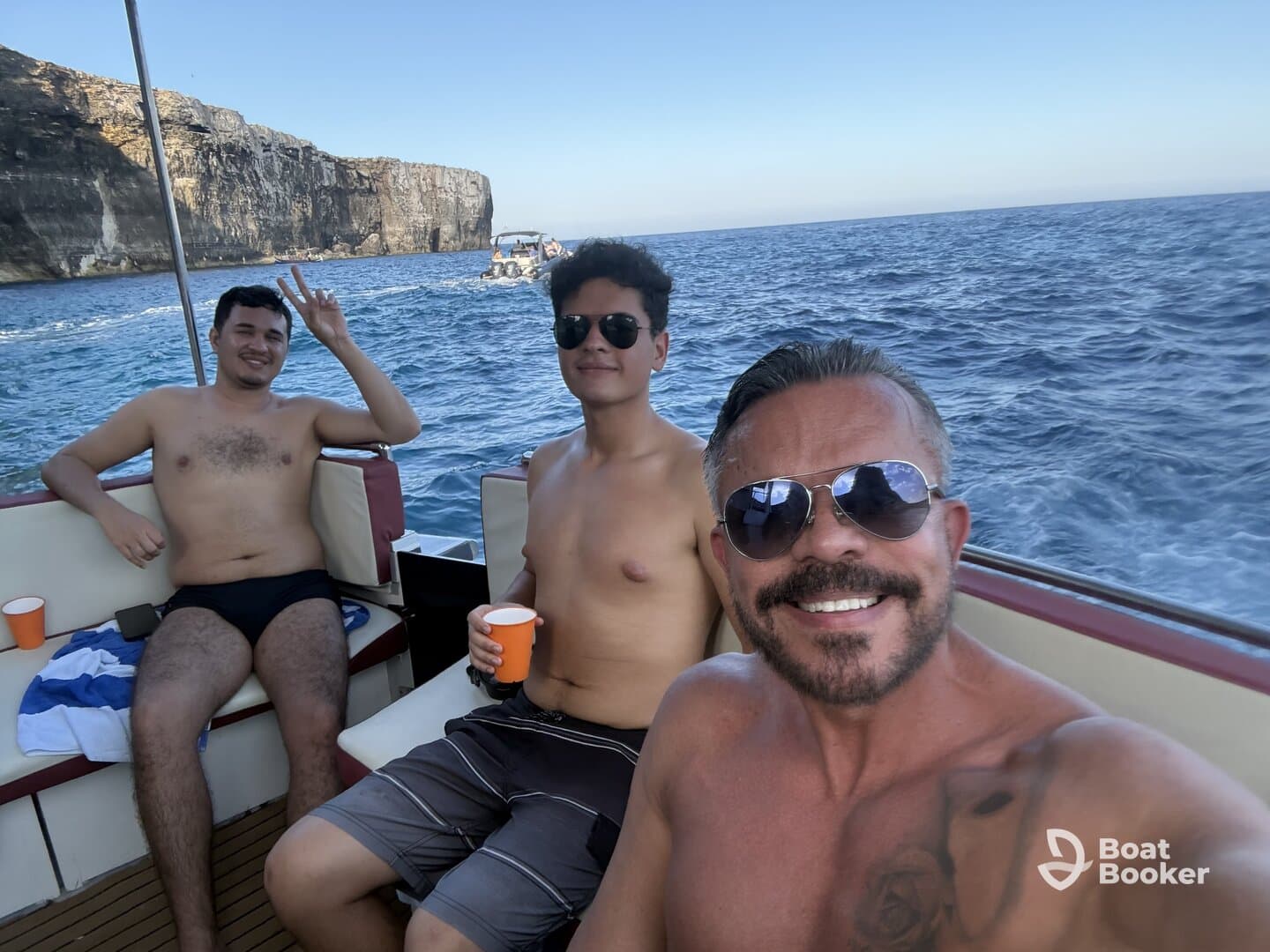 A group of friends enjoys a fun day on the water, capturing smiles and camaraderie aboard their boat, with stunning coastal cliffs in the background.