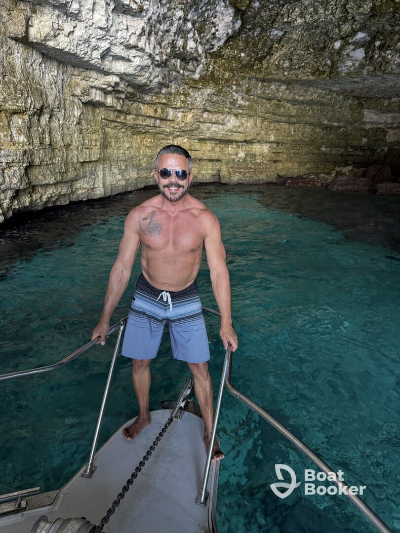 A man stands on the bow of a boat in a stunning cave, showcasing the beauty of adventure on the water. Perfect for exploring hidden gems and enjoying the crystal-clear waters.