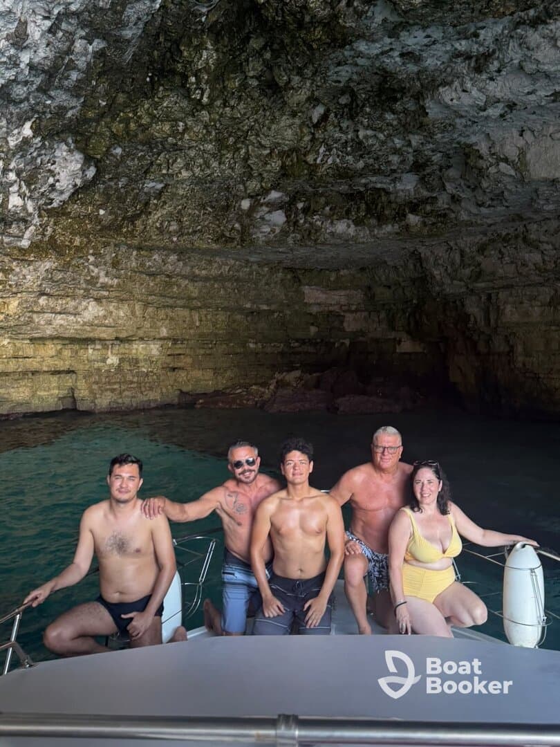 A cheerful group poses on a boat inside a stunning cave, capturing a memorable moment during their aquatic adventure.