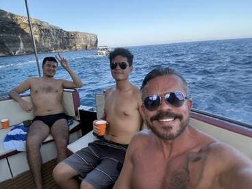 A group of friends enjoys a fun day on the water, capturing smiles and camaraderie aboard their boat, with stunning coastal cliffs in the background.