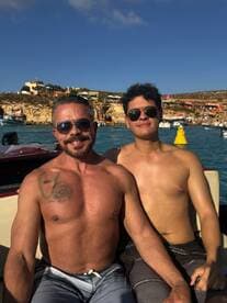 Two friends enjoy a sunny day on the water, capturing a moment of joy aboard a boat with a scenic backdrop.