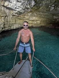 A man stands on the bow of a boat in a stunning cave, showcasing the beauty of adventure on the water. Perfect for exploring hidden gems and enjoying the crystal-clear waters.