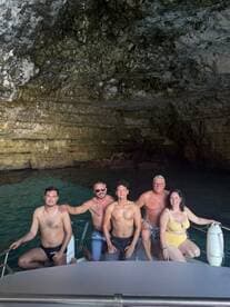 A cheerful group poses on a boat inside a stunning cave, capturing a memorable moment during their aquatic adventure.