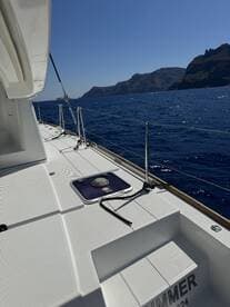 A clear view of the side deck of a yacht, showcasing its sleek design against a backdrop of stunning coastal cliffs and deep blue waters.