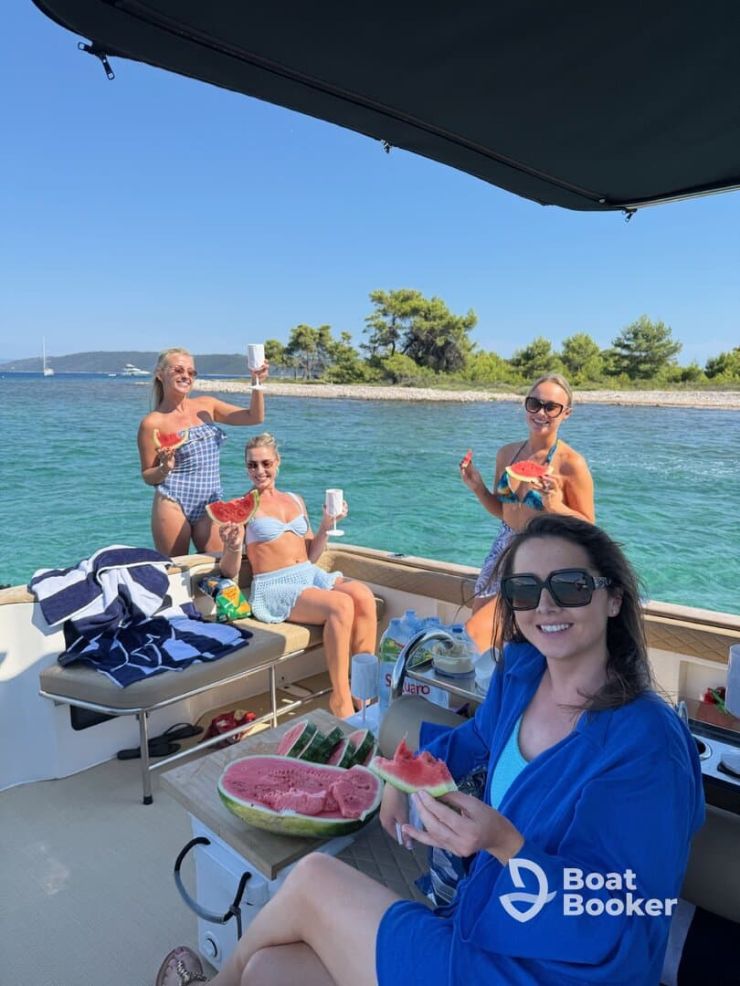 A lively group of friends enjoys a fun day on the water, sharing watermelon and drinks aboard a boat — perfect for summer celebrations and memorable outings.