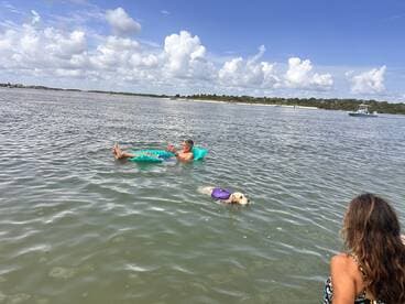 A man relaxes on a floating mat while enjoying the water, accompanied by a dog in a life jacket. This scene captures the essence of leisure and fun in the sun.