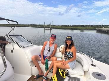 A couple enjoys a relaxing day on the water with their dog, showcasing the perfect blend of companionship and leisure aboard their boat.