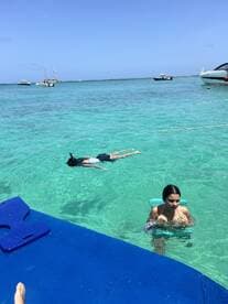 Two individuals enjoy a refreshing swim in crystal-clear waters, with one snorkeling nearby — a perfect snapshot of fun and adventure on the water.