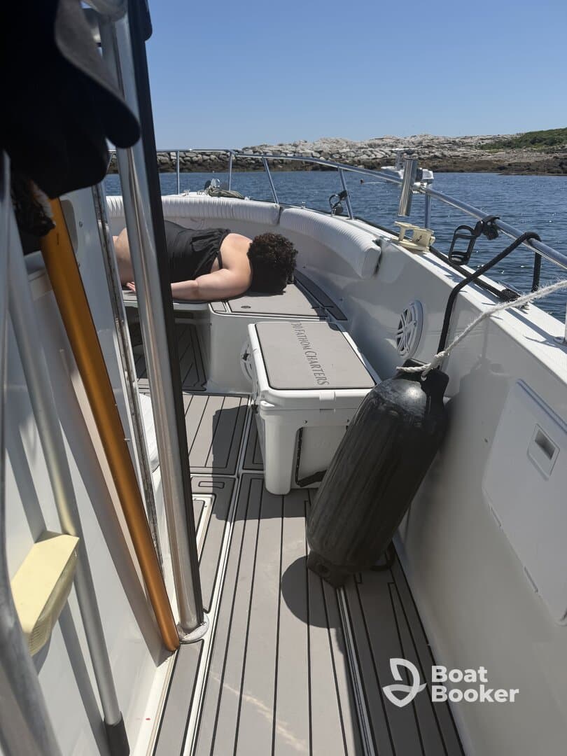 A person relaxes on the deck of a boat, showcasing the comfortable seating area — perfect for lounging during a day on the water.