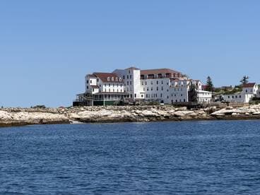 A distant view of a coastal building near the water, with rocky shores in the foreground. The image lacks clarity and detail.
