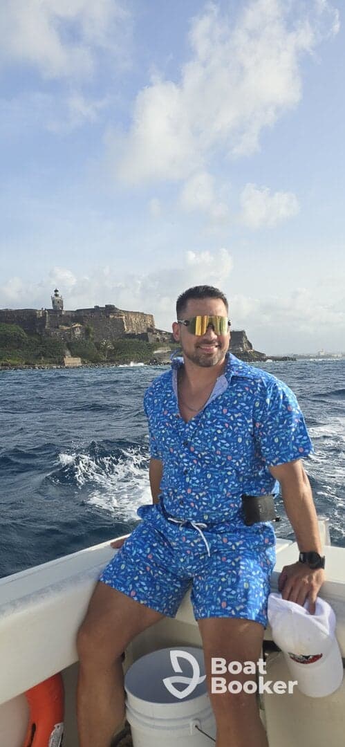 A man enjoys a scenic boat ride with a historic coastline in the background, capturing the essence of adventure on the water.