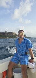 A man enjoys a scenic boat ride with a historic coastline in the background, capturing the essence of adventure on the water.