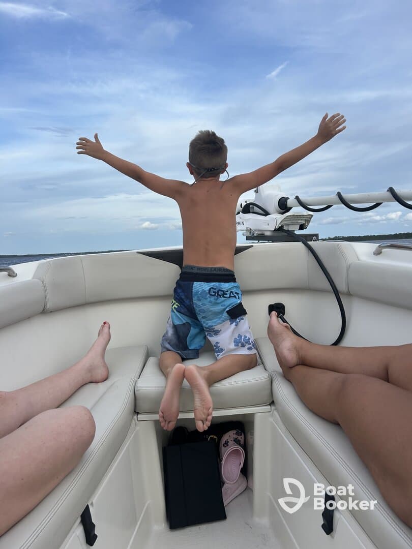 A joyful child spreads his arms wide on a boat, embracing the thrill of the ride — a perfect moment of fun and freedom on the water.