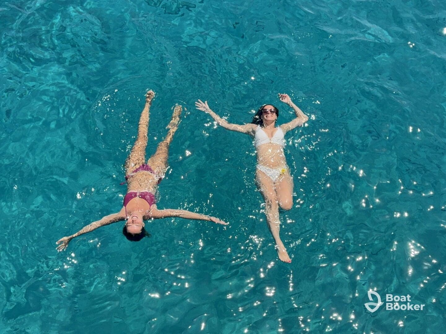 Two friends enjoy a refreshing swim in crystal-clear waters, capturing the essence of summer fun and relaxation on a boating adventure.