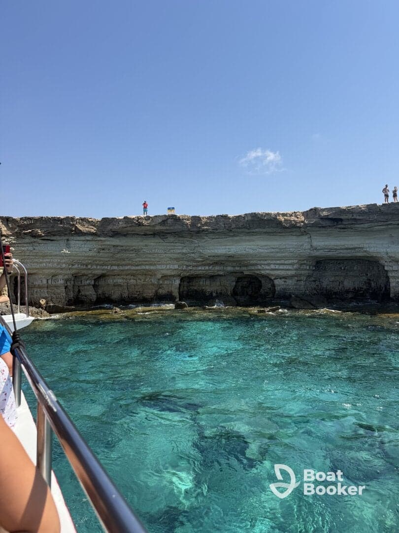 A stunning view of a rocky coastline with clear turquoise waters, showcasing guests enjoying a boat trip — perfect for exploring beautiful marine landscapes.