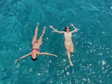 Two friends enjoy a refreshing swim in crystal-clear waters, capturing the essence of summer fun and relaxation on a boating adventure.