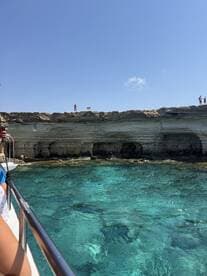 A stunning view of a rocky coastline with clear turquoise waters, showcasing guests enjoying a boat trip — perfect for exploring beautiful marine landscapes.