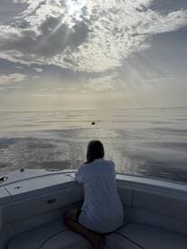 A serene moment as a woman gazes out over calm waters, reflecting the beauty of the sky — perfect for peaceful sunset cruises.