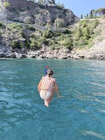 A child joyfully jumps into the clear blue waters, ready for a snorkeling adventure — a perfect moment capturing the excitement of summer fun on the water.