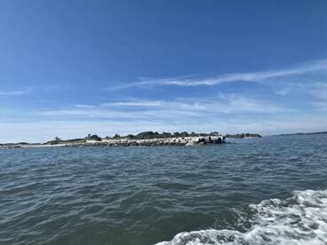 A picturesque view of a rocky coastline under a clear blue sky, showcasing the beauty of the surrounding waters and natural landscape.