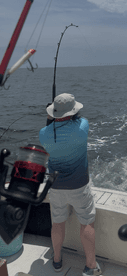 A fisherman battles a catch on the open water, showcasing the excitement of deep-sea fishing adventures.