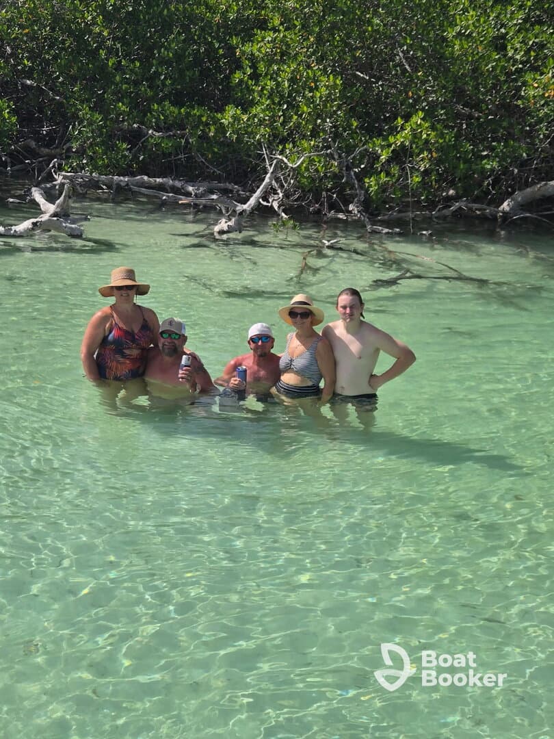 A cheerful group enjoys a refreshing swim in clear waters surrounded by mangroves, capturing the essence of a fun day on the water.