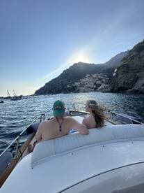 A couple enjoys a scenic boat ride along the stunning Amalfi Coast, with picturesque cliffs and charming villages in the background, perfect for romantic getaways.