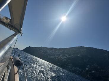 A stunning view of a boat underway, capturing the sparkling water and coastal landscape under a bright sun — perfect for showcasing the beauty of a day on the water.