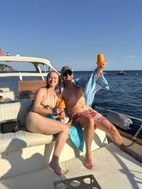 A joyful couple enjoys cocktails on a boat under the sun, capturing the essence of a perfect day on the water.