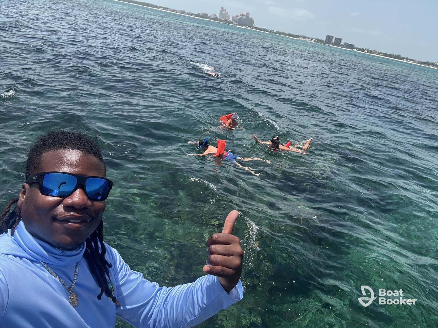 A group enjoys snorkeling in clear waters, with a friendly guide giving a thumbs up — a perfect snapshot of adventure and fun in the ocean.