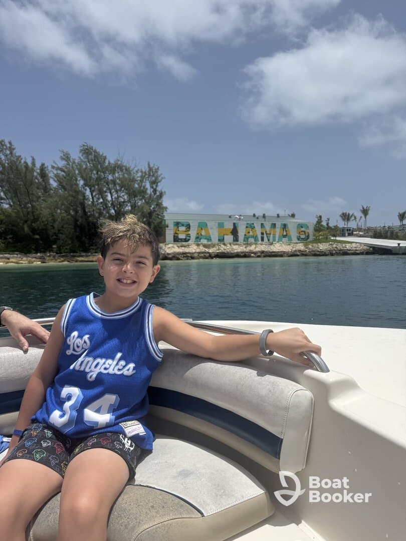 A cheerful child enjoys a boat ride in the Bahamas, with vibrant 'Bahamas' signage in the background — a perfect snapshot of family fun on the water.