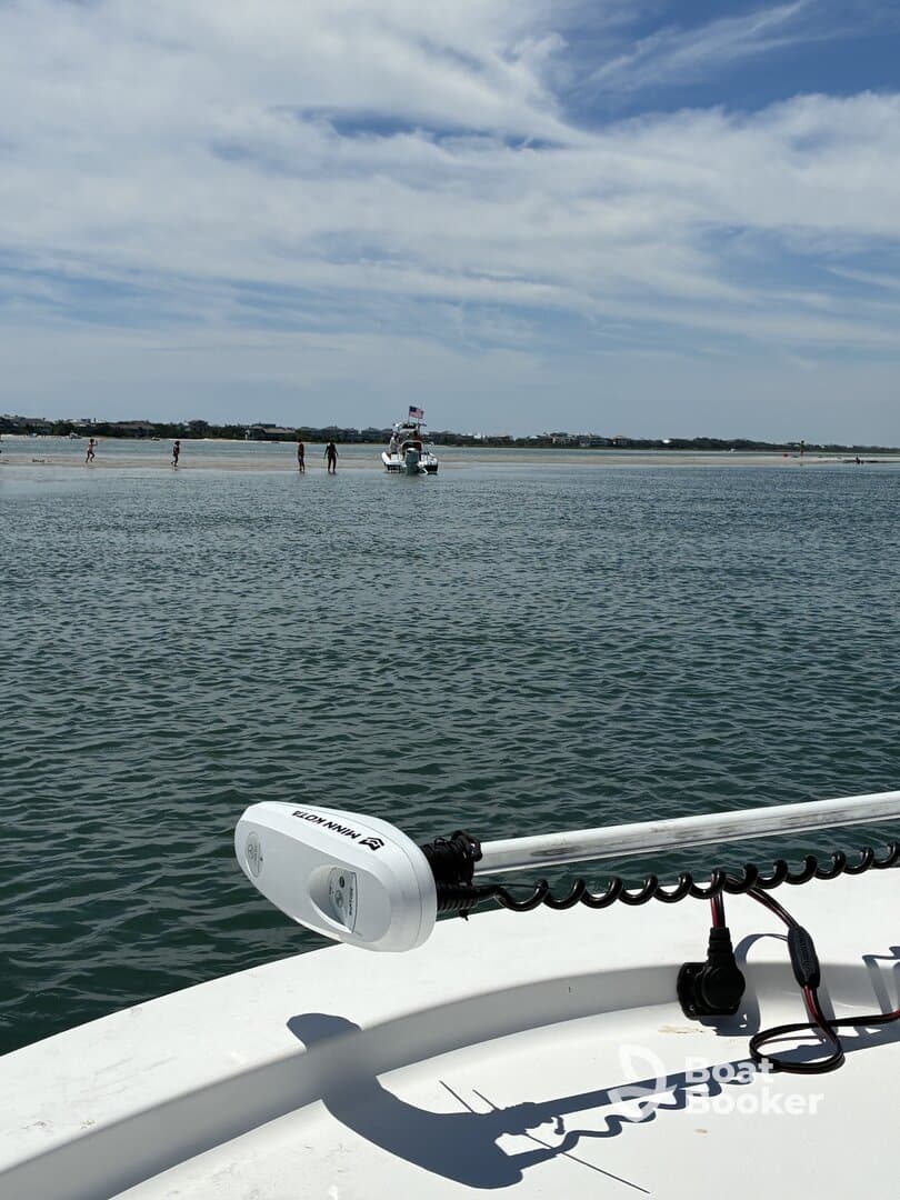 A scenic view of a boat near a sandbar with people enjoying the shallow waters, perfect for a day of relaxation and fun on the water.