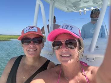 Two friends take a cheerful selfie aboard a boat, enjoying a sunny day on the water — perfect for capturing memorable moments during a boating adventure.