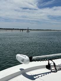 A scenic view of a boat near a sandbar with people enjoying the shallow waters, perfect for a day of relaxation and fun on the water.
