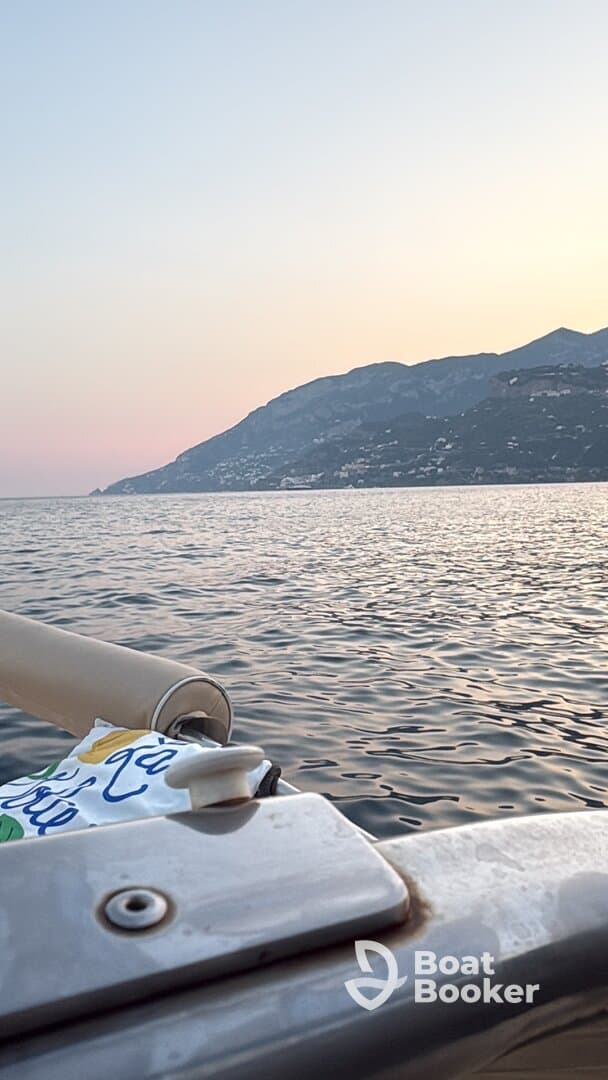 A serene view from a boat at sunset, showcasing the calm waters and distant mountains — perfect for peaceful evening cruises.